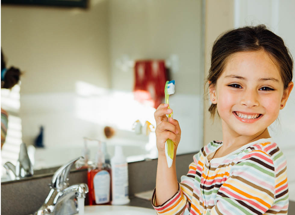 Girl brushes teeth PCI Pediatrics article about daily oral health for children.