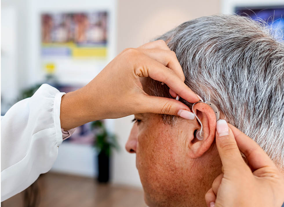 Audiologist helps patient with hearing aids.